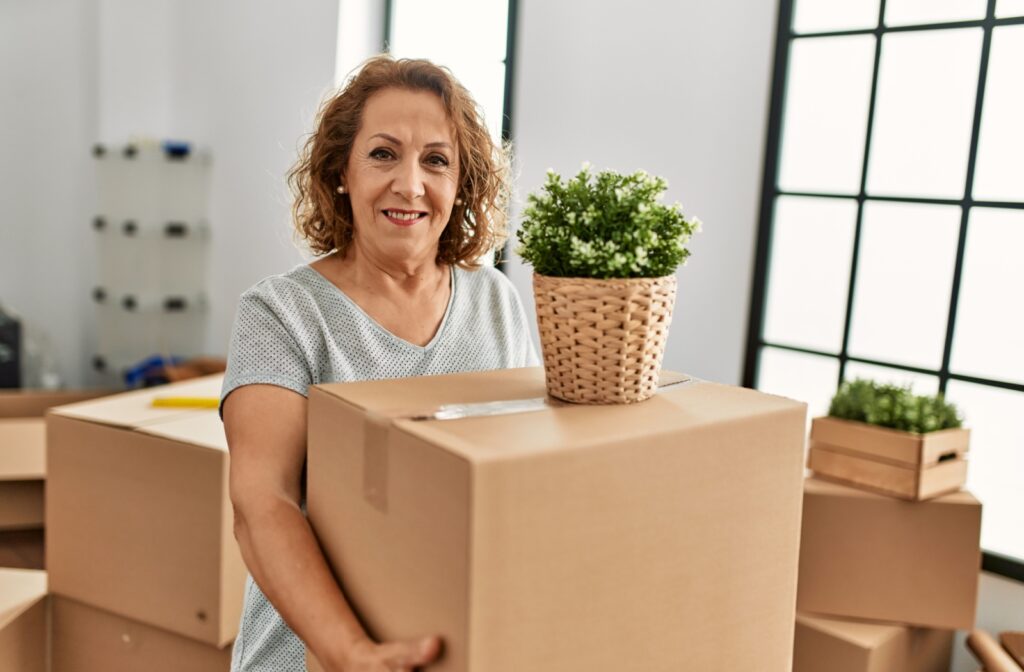 Someone is carrying a moving box with a plant on top.